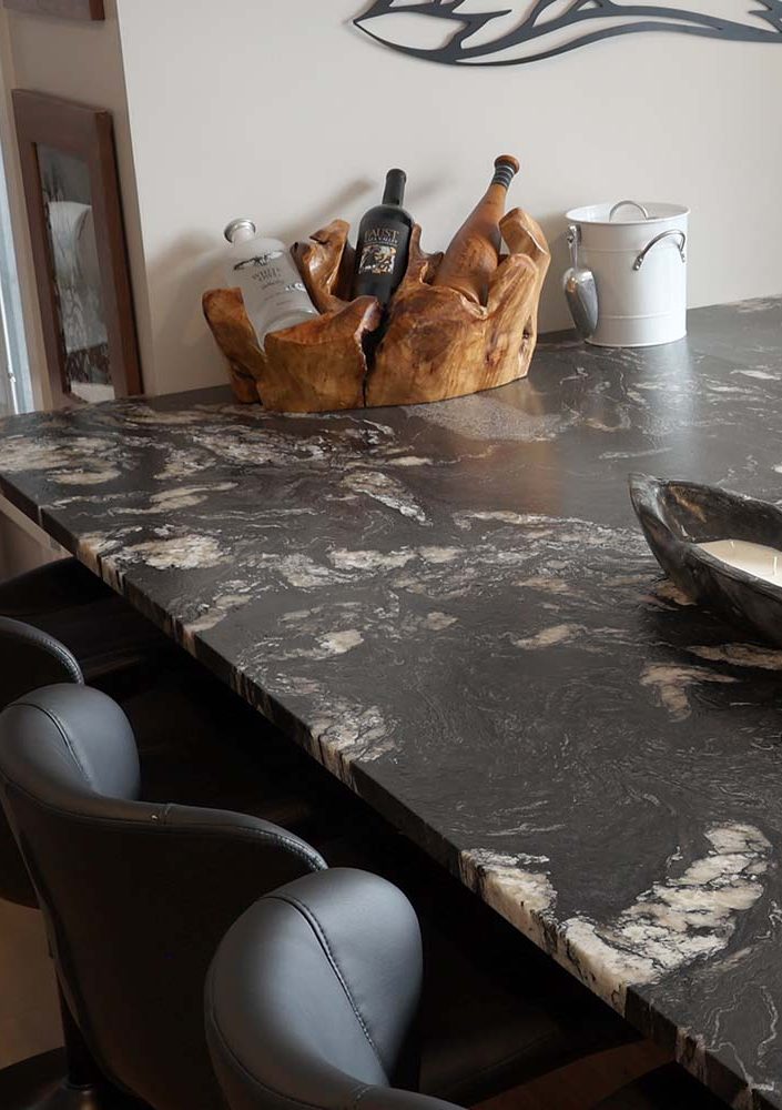3 bottles of wine sitting in a wooden holder on a black and white marble countertop