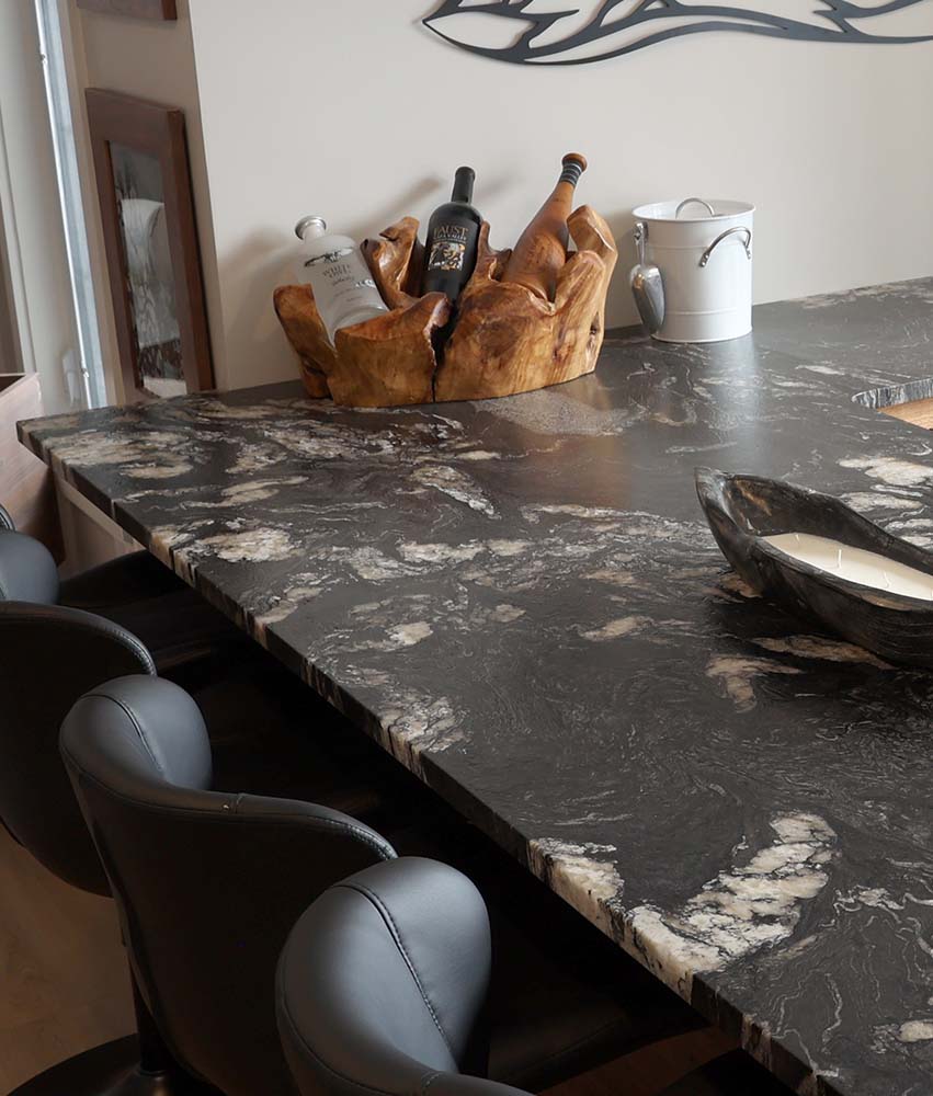 3 bottles of wine sitting in a wooden holder on a black and white marble countertop