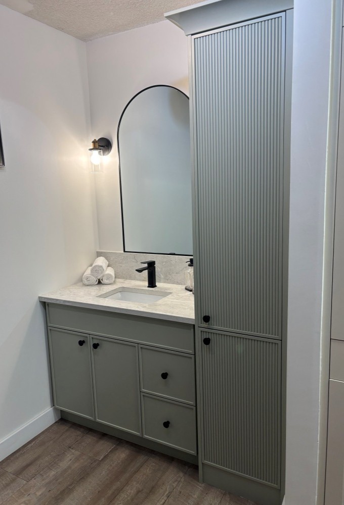 A well-lit bathroom showcasing a vanity with a sink and a mirror, reflecting a tidy and modern design with soft color tones.